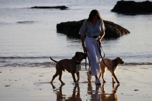 Educadora canina paseando con dos perros por la playa de Santander